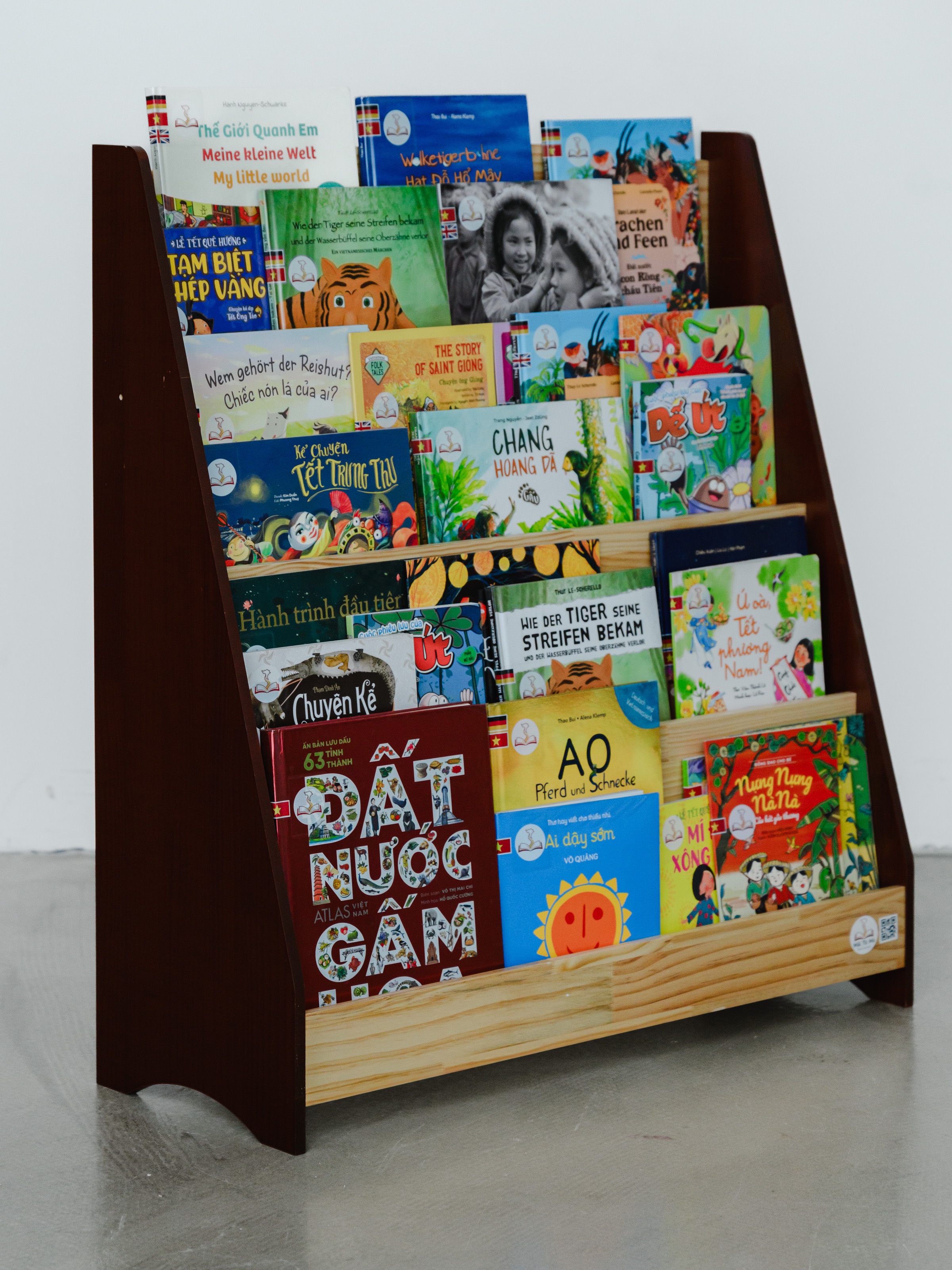 A brown Mãi Tò Mò book shelf with Vietnamese children’s books